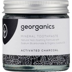 Frasco de vidrio con dentífrico de crema de coco y carbón activo de Georganics para un blanqueamiento dental natural.