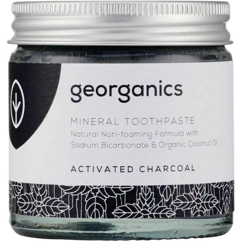 Frasco de vidrio con dentífrico de crema de coco y carbón activo de Georganics para un blanqueamiento dental natural.